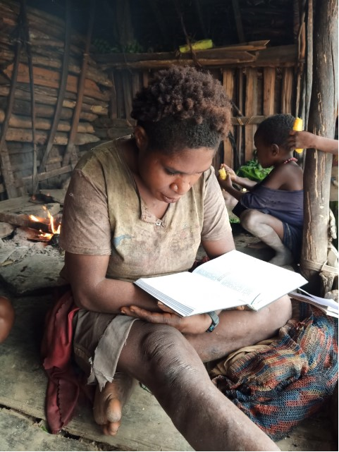 Moi woman reading Bible in a hut