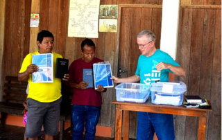 missionary with friends holding up Bible portions for dedication ceremony