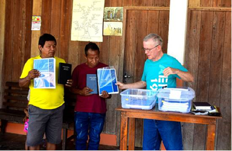 missionary with friends holding up Bible portions for dedication ceremony