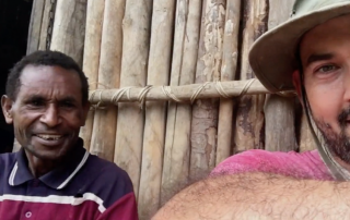 Ben Hatton and Paison sitting by a wooden hut