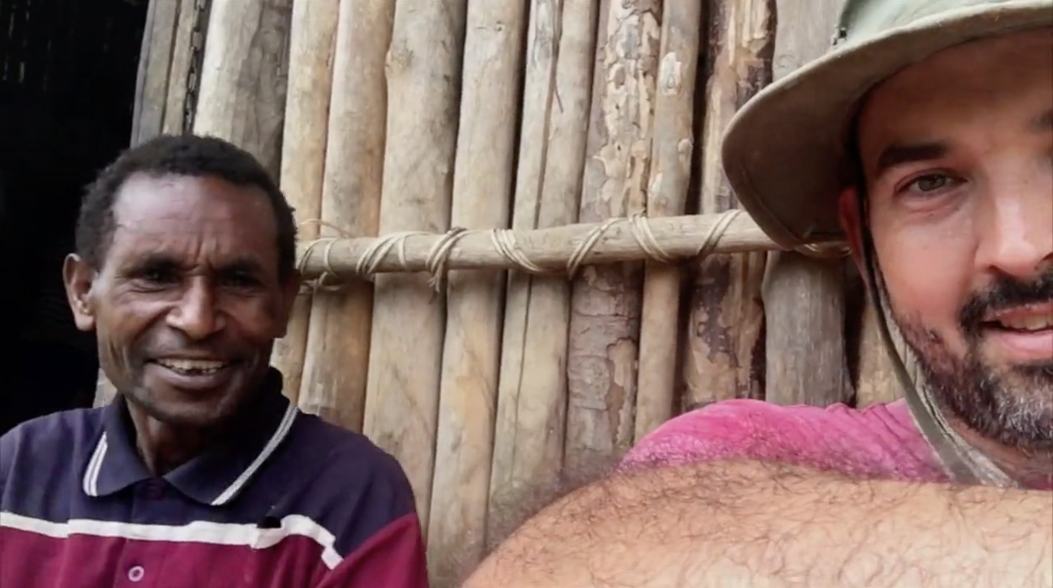 Ben Hatton and Paison sitting by a wooden hut