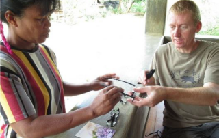 Grant Bayfield handing glasses to Manobo woman