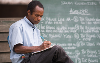 Dinangat man with a notebook in front of a chalk board