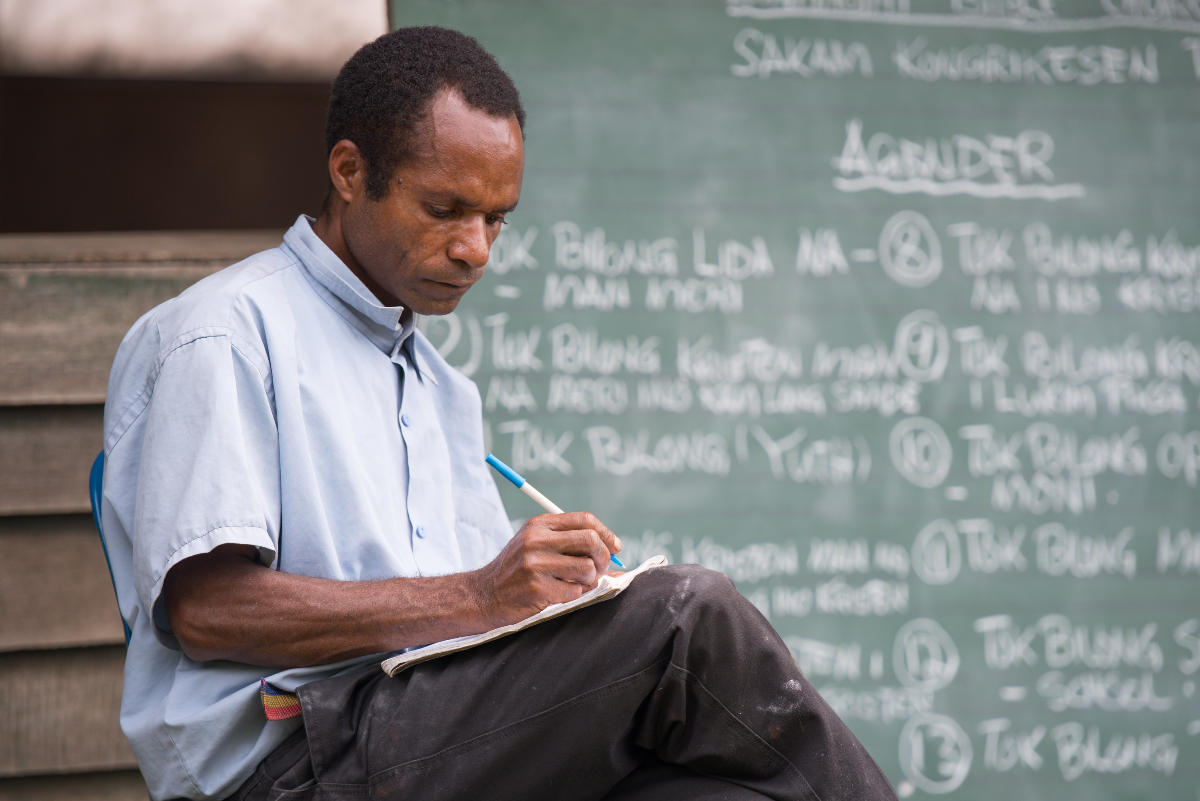 Dinangat man with a notebook in front of a chalk board