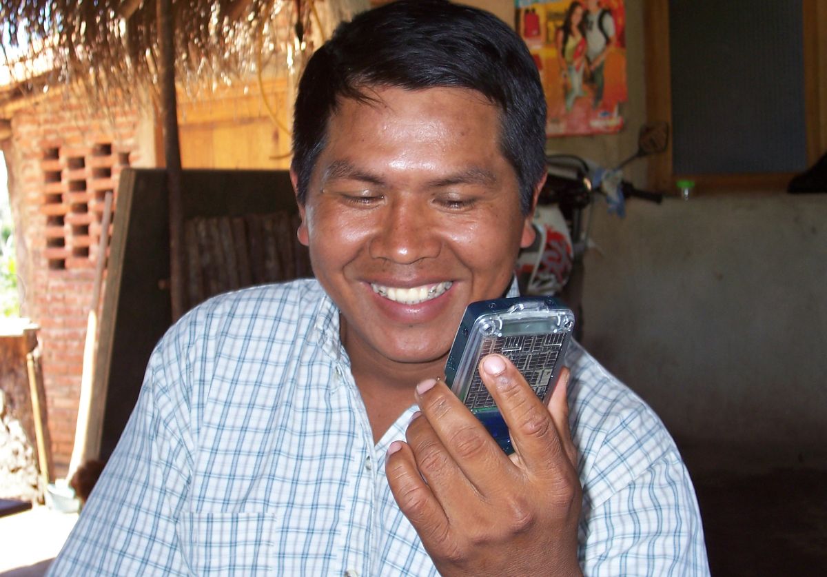 man smiles while holding audio Bible