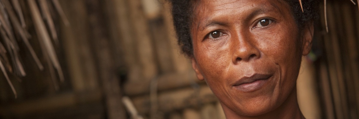 smiling woman by thatch house