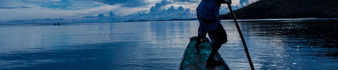 man poling canoe in the water